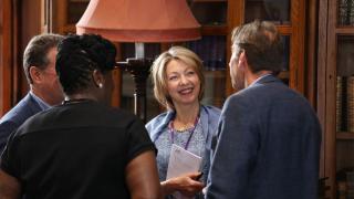 Woman smiling and listening to a group.