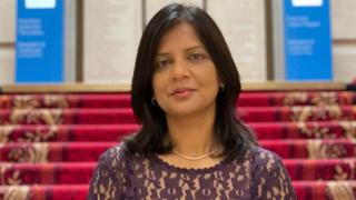 Priti smiling in front of stairs