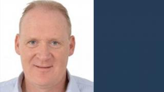 Graeme smiling in front of white background