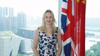 Jo smiling and standing in front of British flag